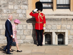 caption: Queen Elizabeth II and President Biden walk at Windsor Castle on Sunday in Windsor, England. This is Biden's first private meeting with Queen Elizabeth II since becoming president.