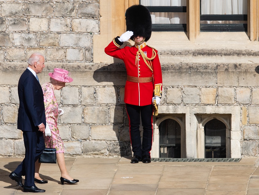 caption: Queen Elizabeth II and President Biden walk at Windsor Castle on Sunday in Windsor, England. This is Biden's first private meeting with Queen Elizabeth II since becoming president.