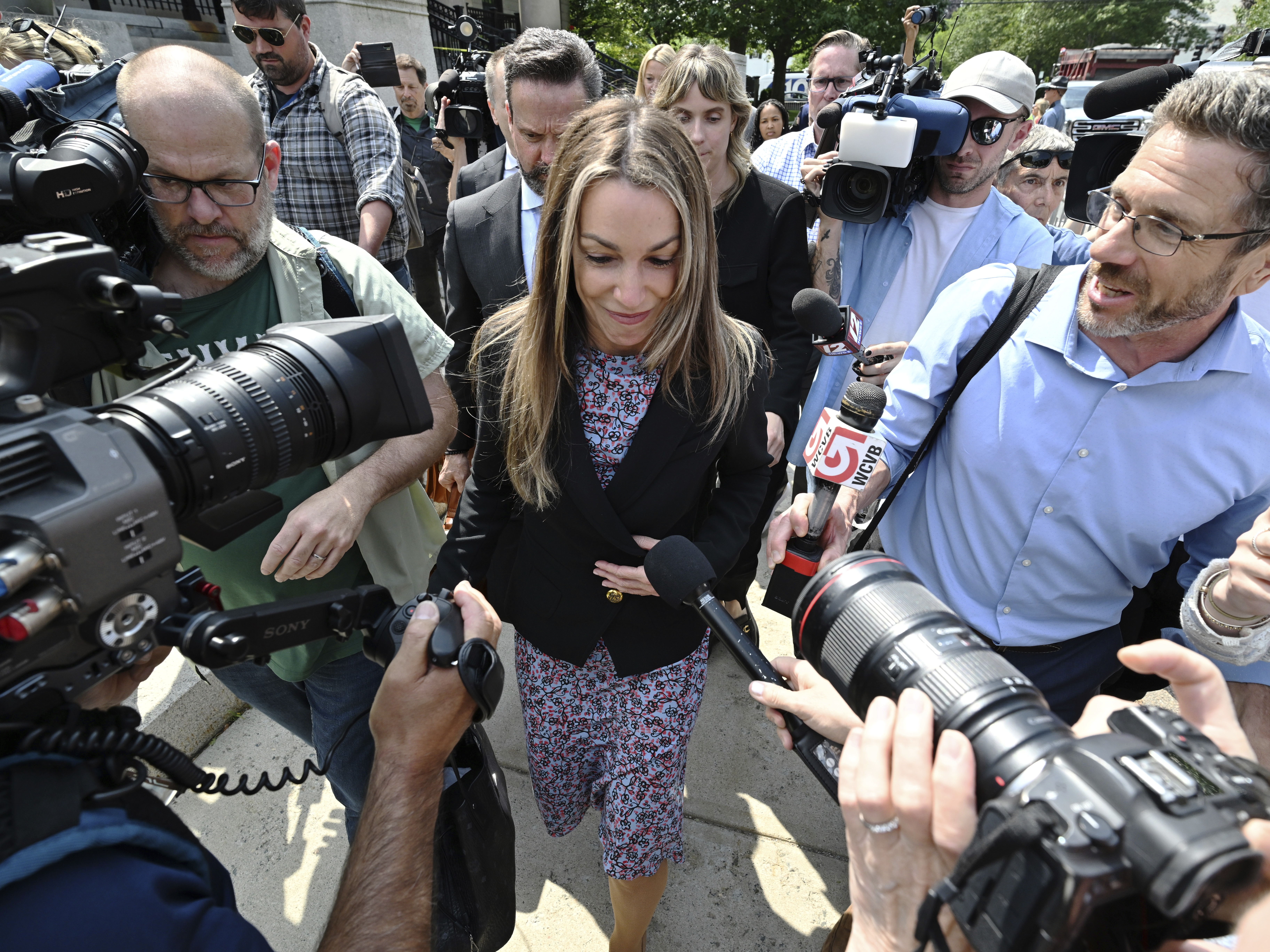 caption: Karen Read is surrounded by reporters as she and her legal team leave the Dedham, Mass., courthouse on Friday, when the jury began deliberations.