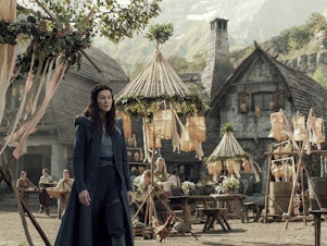 caption: Moiraine (Rosamund Pike) visits a remote village in search of something — or someone — in Amazon's <em>The Wheel of Time</em>.