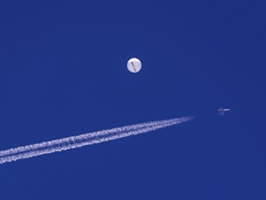 caption: A fighter jet flies near a large balloon drifting above the Atlantic Ocean, just off the coast of South Carolina near Myrtle Beach, Feb. 4. Minutes later, the balloon was struck by a missile from an F-22 fighter jet, ending its weeklong traverse over the United States. China said the balloon was a weather research vessel blown off course, a claim rejected by U.S. officials.