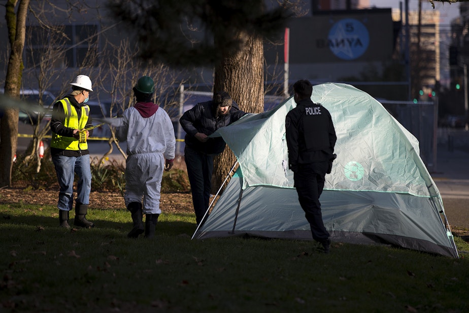 caption: Robert DeWitt takes down his tent as Seattle Police and Seattle Parks and Recreation arrive to set up a perimeter before sweeping unhoused people from Denny Park on Wednesday, March 3, 2021, in Seattle. DeWitt had stayed overnight with the hopes of talking with outreach services but was only approached by police. 