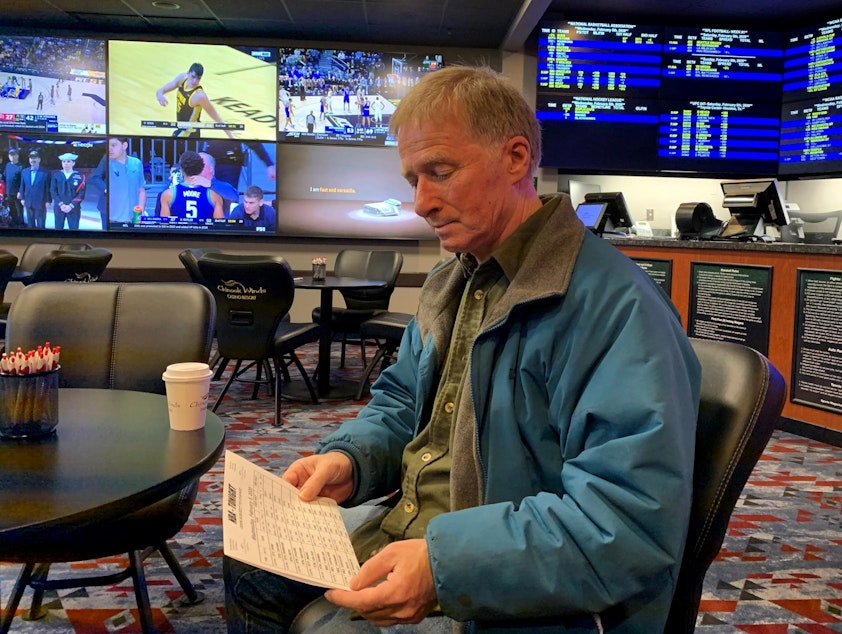 caption: Football and basketball fan David Salisbury studying the daily odds at the Chinook Winds Casino sportsbook in Lincoln City, Oregon.