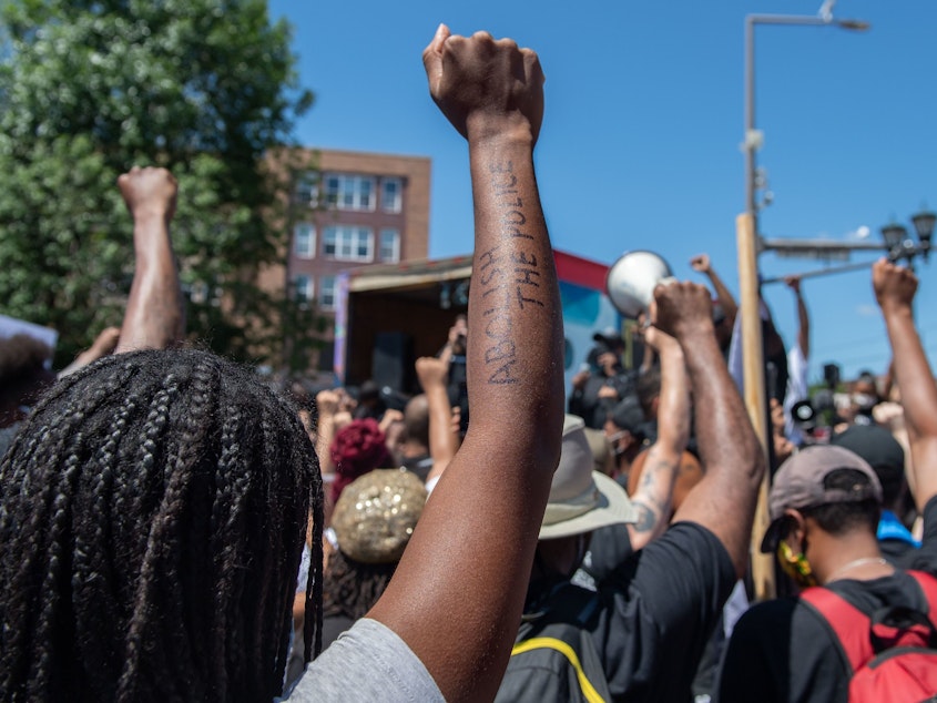 caption: People raise their fists in a moment of silence for George Floyd on in St. Paul, Minn., in July.