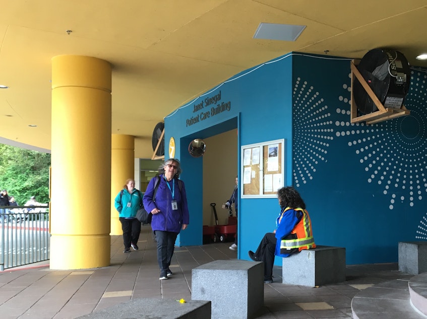 caption: Giant fans push air away from an entrance to Seattle Children's Hospital. A sign on the fans says, "Please keep fans on during weekday construction hours."