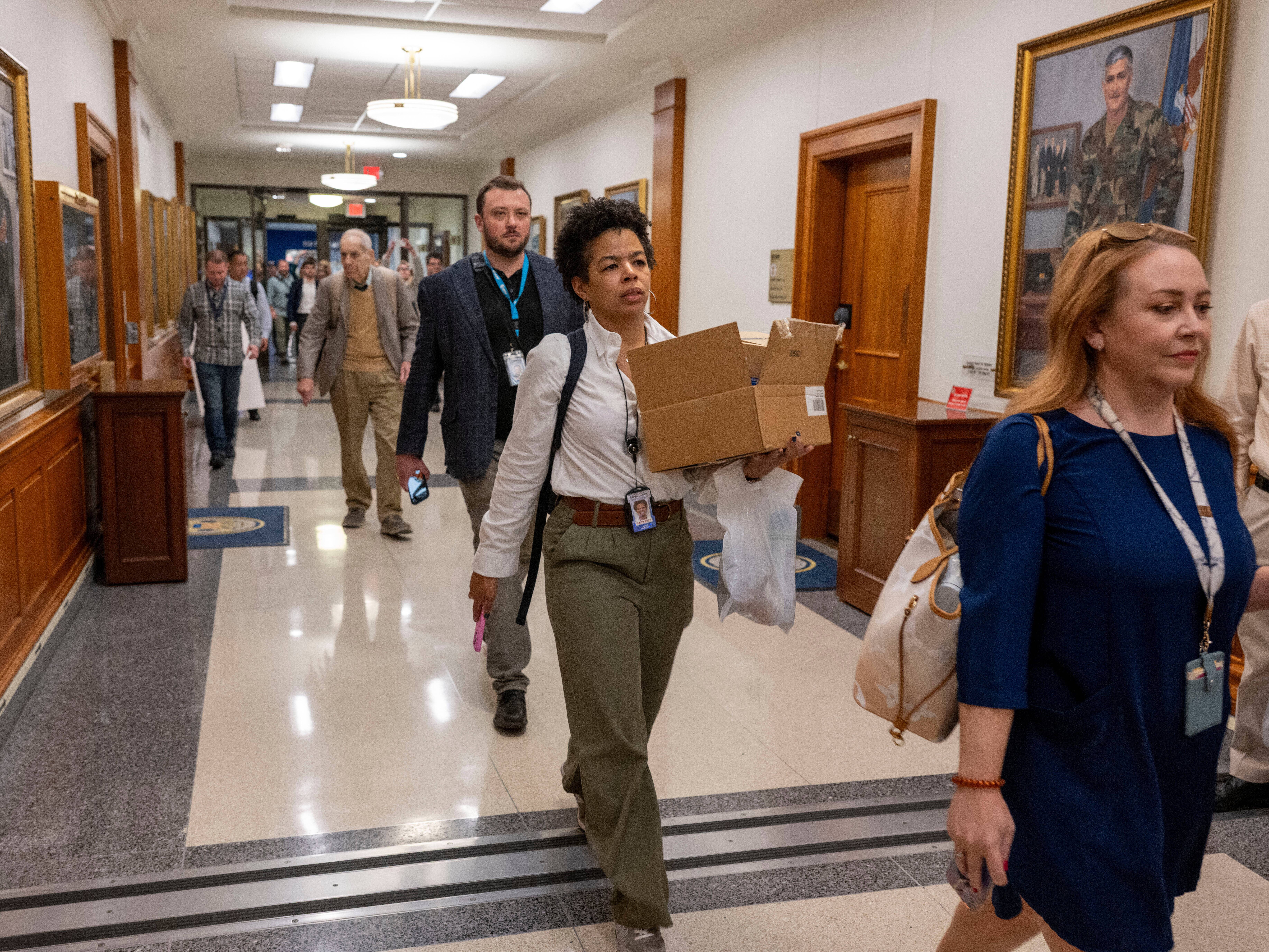 caption: Members of the Pentagon press corps walk out of the Pentagon as a group after turning in their press credentials on Wednesday, Oct. 15, 2025. On Thursday, <em>The New York Times</em> sued the Defense Department and Secretary Pete Hegseth over its new media policy.