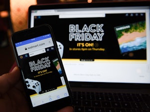 caption: A picture taken in Liverpool, north west England on November 22, 2018 shows Black Friday sales branding on shopping websites displayed on smartphone and laptop screens.
