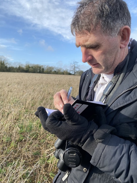 caption: Twitcher Lee Evans marks down his latest bird find in his notebook. He's identified 594 different bird species through the UK and Ireland.  