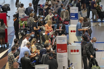 caption: People line up to get on an Air France flight to Paris at OR Tambo's airport in Johannesburg, South Africa, on Friday as several countries announced travel bans in response to the omicron variant of the coronavirus.