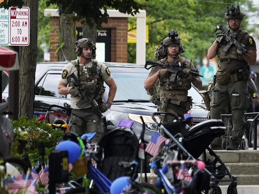 caption: Law enforcement personnel secure the scene after a mass shooting Monday at a Fourth of July parade in downtown Highland Park, a Chicago suburb.