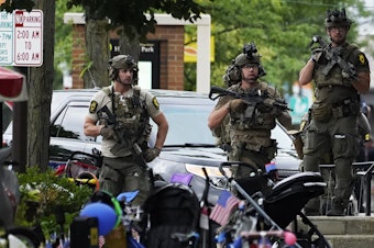 caption: Law enforcement personnel secure the scene after a mass shooting Monday at a Fourth of July parade in downtown Highland Park, a Chicago suburb.