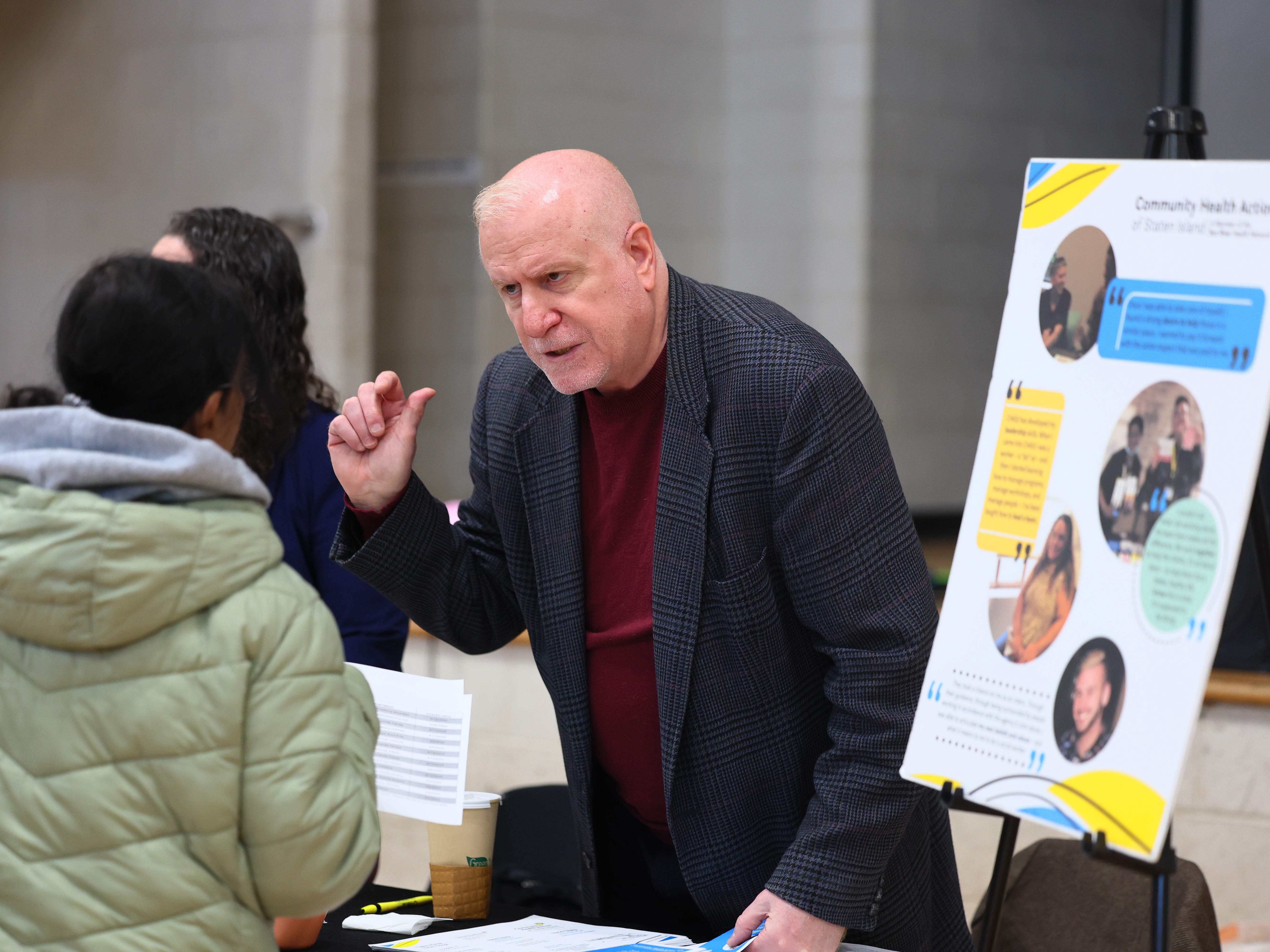 caption: Employers speak with attendees during a job fair at the YMCA Gerard Carter Center in Staten Island in New York City on March 27, 2025. Employers continued to add jobs in March, but uncertainty over trade policy and softer spending by consumers could soon be a drag on hiring.