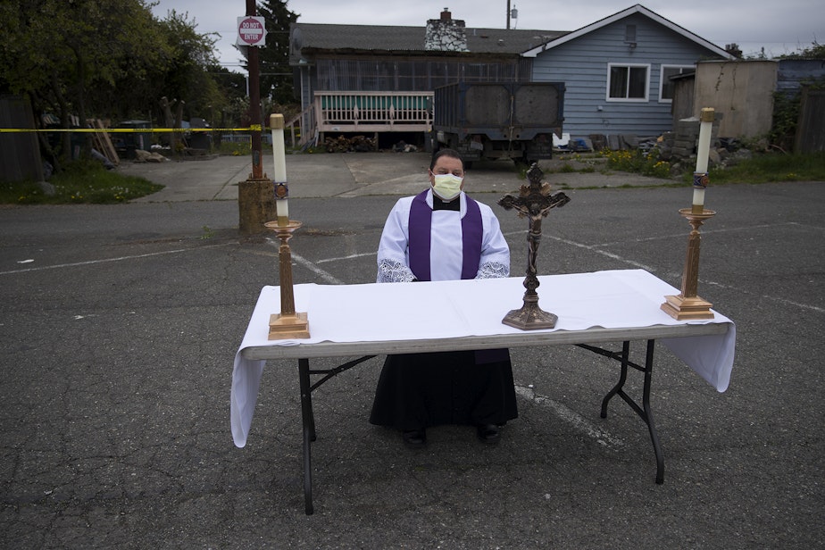 caption: Father Jose Alvarez waits for people to arrive for walk and drive through confessions on Friday, April 24, 2020, in the parking lot at Holy Family Roman Catholic Church in White Center. 