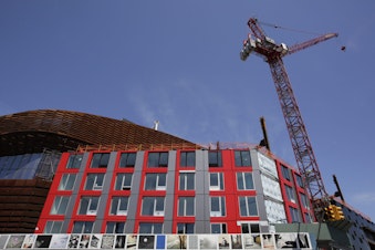 caption: A construction crane towers over a modular apartment building next to the Barclay's Center, Monday, May 5, 2014 in the Brooklyn borough of New York. (AP Photo/Mark Lennihan)