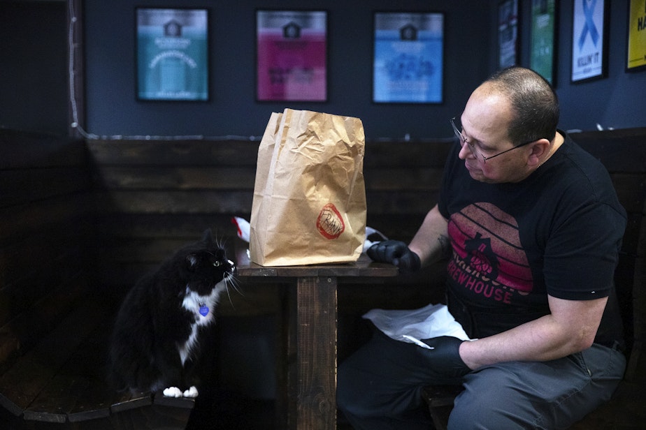 caption: Frank Castro, owner of Bickersons Brewhouse, takes a lunch break with Simcoe the cat, on Wednesday, January 31, 2024, in Seattle.  