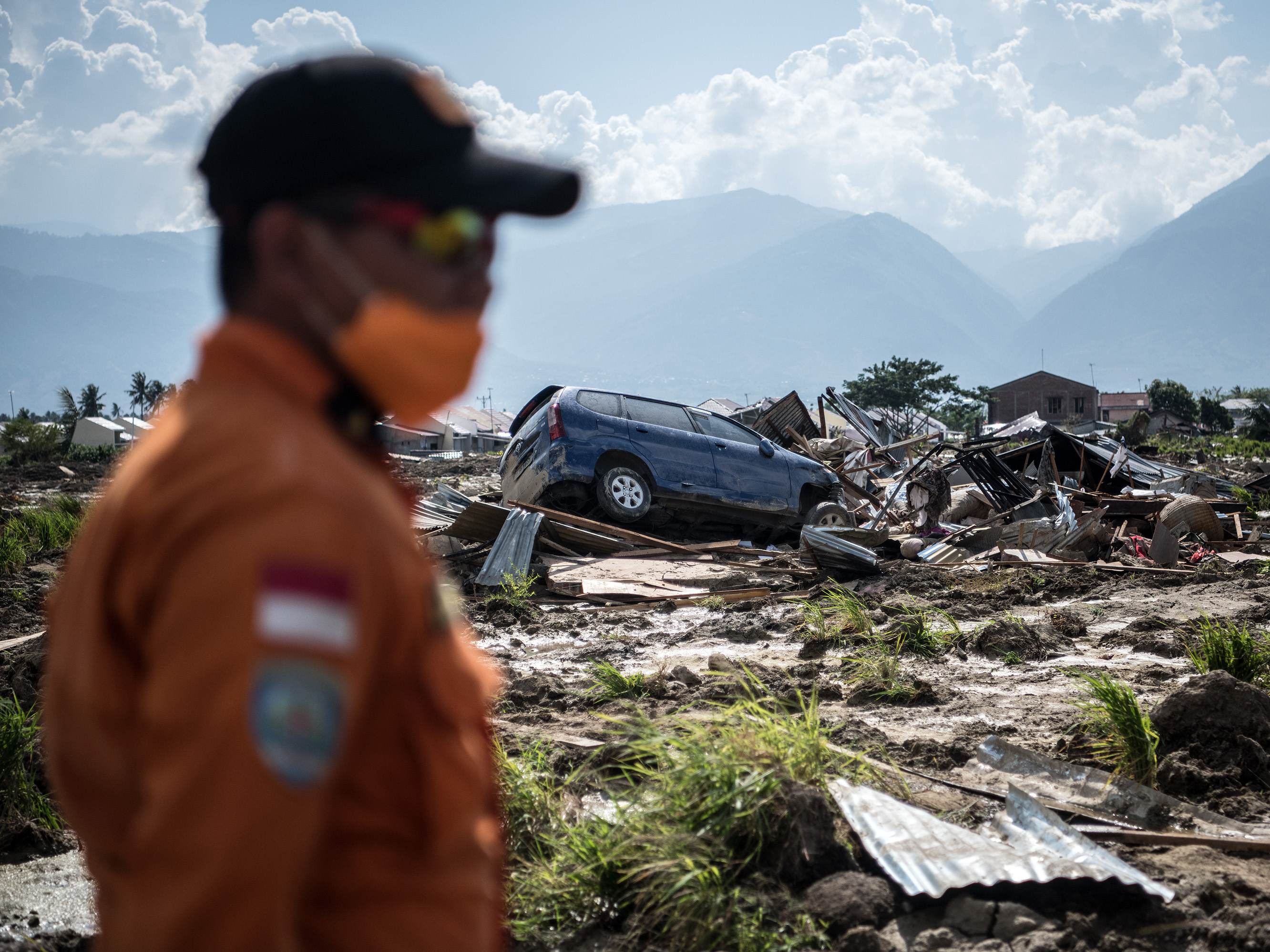caption: A search-and-rescue team member scans the ruins of an area in Palu, on the Indonesian island of Sulawesi on Thursday. Of the more than 1,500 people who died in the disaster, authorities say more than 1,200 lived in Palu.