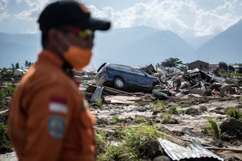 caption: A search-and-rescue team member scans the ruins of an area in Palu, on the Indonesian island of Sulawesi on Thursday. Of the more than 1,500 people who died in the disaster, authorities say more than 1,200 lived in Palu.
