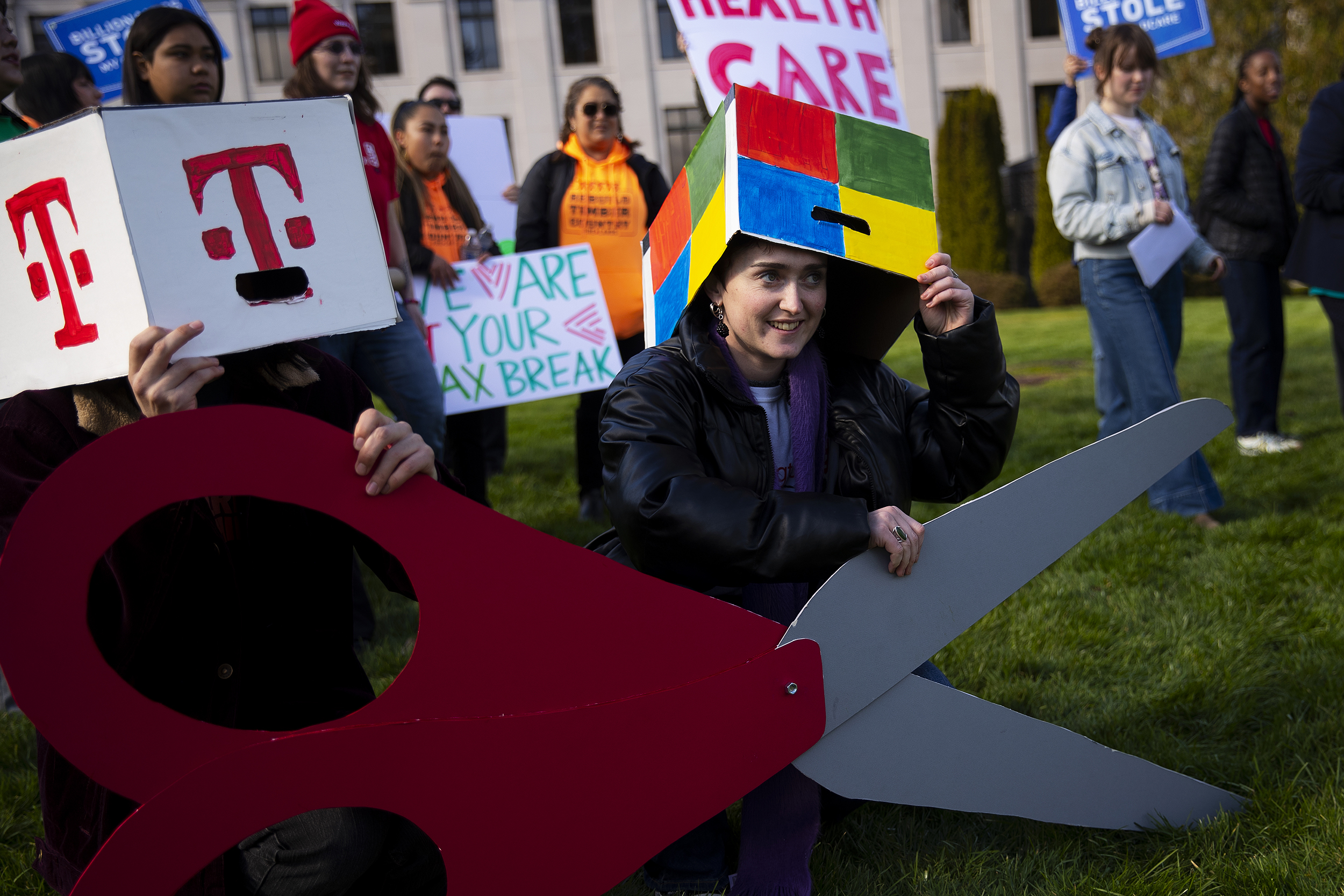 caption: Emma LeFever, with Washington CAN, smiles before a group photo  following a rally against tax cuts for corporations on Thursday, February 26, 2026, at the Washington State Capitol campus in Olympia. 