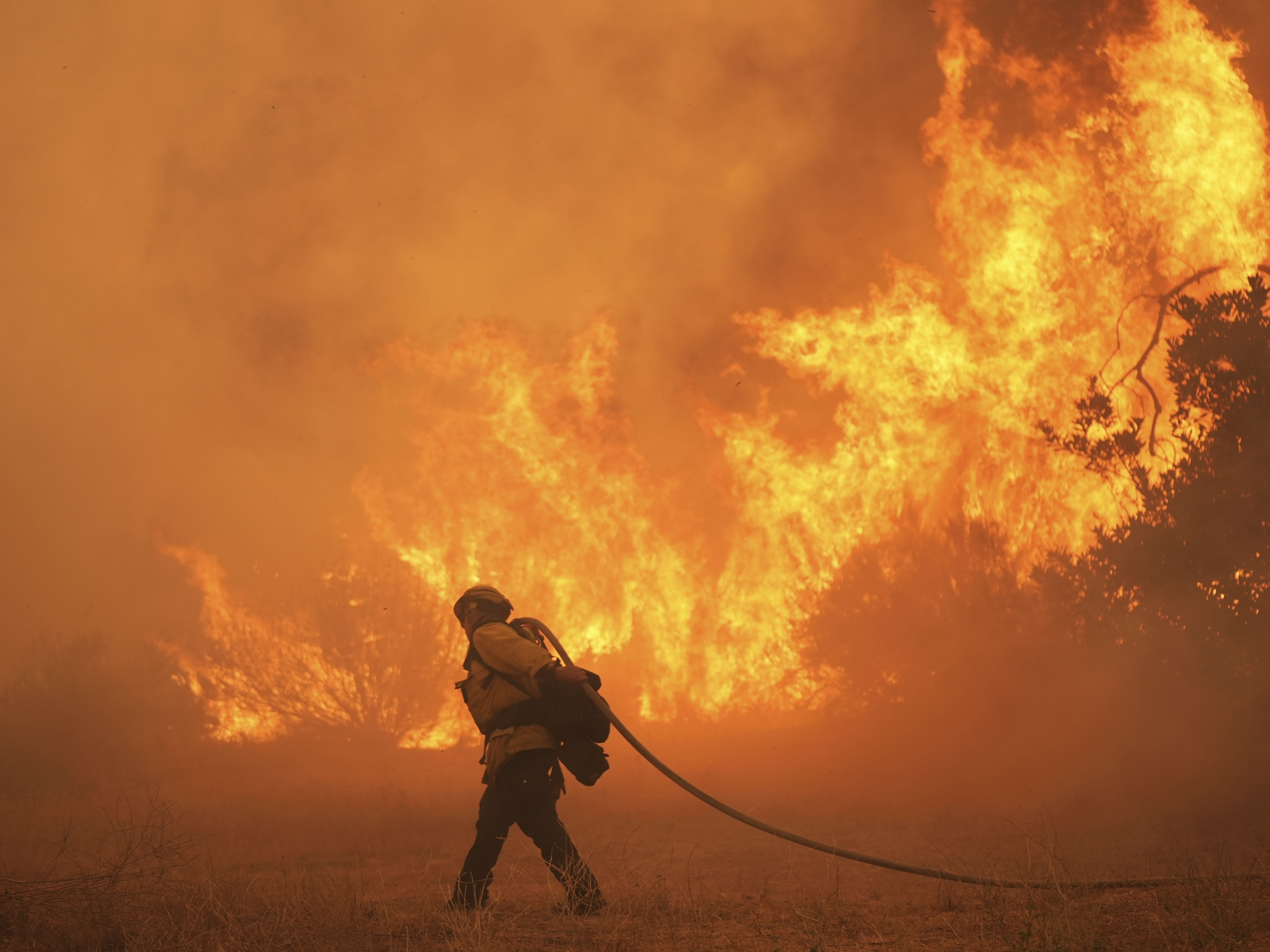 caption: A firefighter battles the Canyon Fire in August in Hasley Canyon, Calif. As temperatures rise with human-caused climate change, wildfire risk is getting worse.