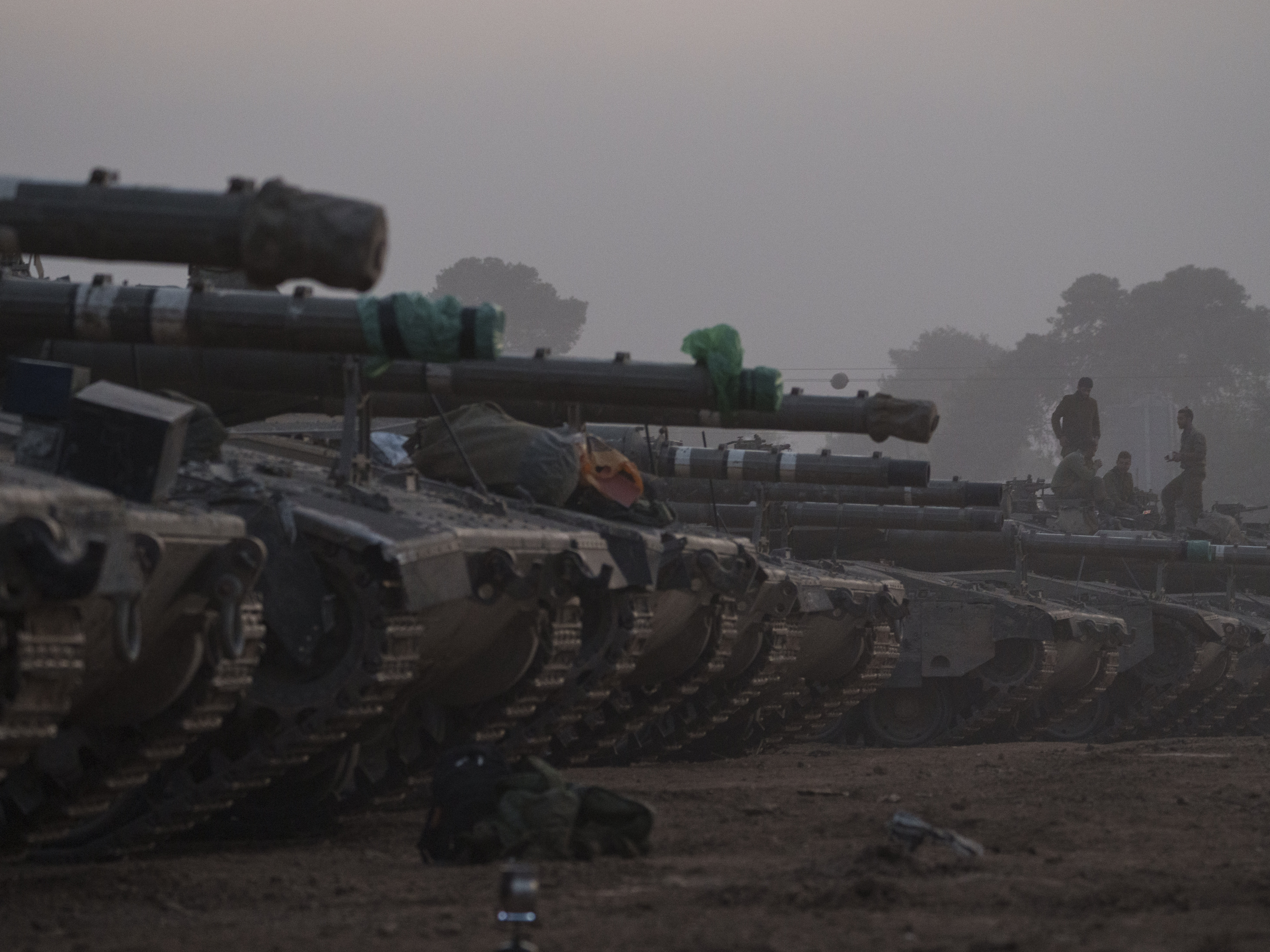 caption: Israeli soldiers stand on top of a tank in a staging area at the Israeli-Gaza border in southern Israel, on Monday.