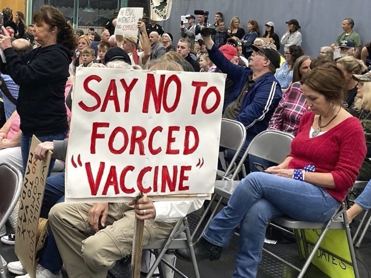 caption: At a meeting in Concord, New Hampshire, on Oct. 13, 2021, audience members voice opposition to federal vaccine mandates. Some employers, from state governments to hospitals to private companies, have already begun enforcing their own vaccine mandates, leading to the resignation or firing of a small percentage of workers.