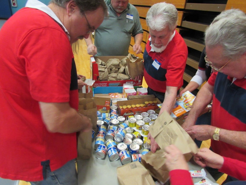 caption: Volunteers from the Elks in Seattle and Shoreline pack take away bags for needy vets at a stand down event.