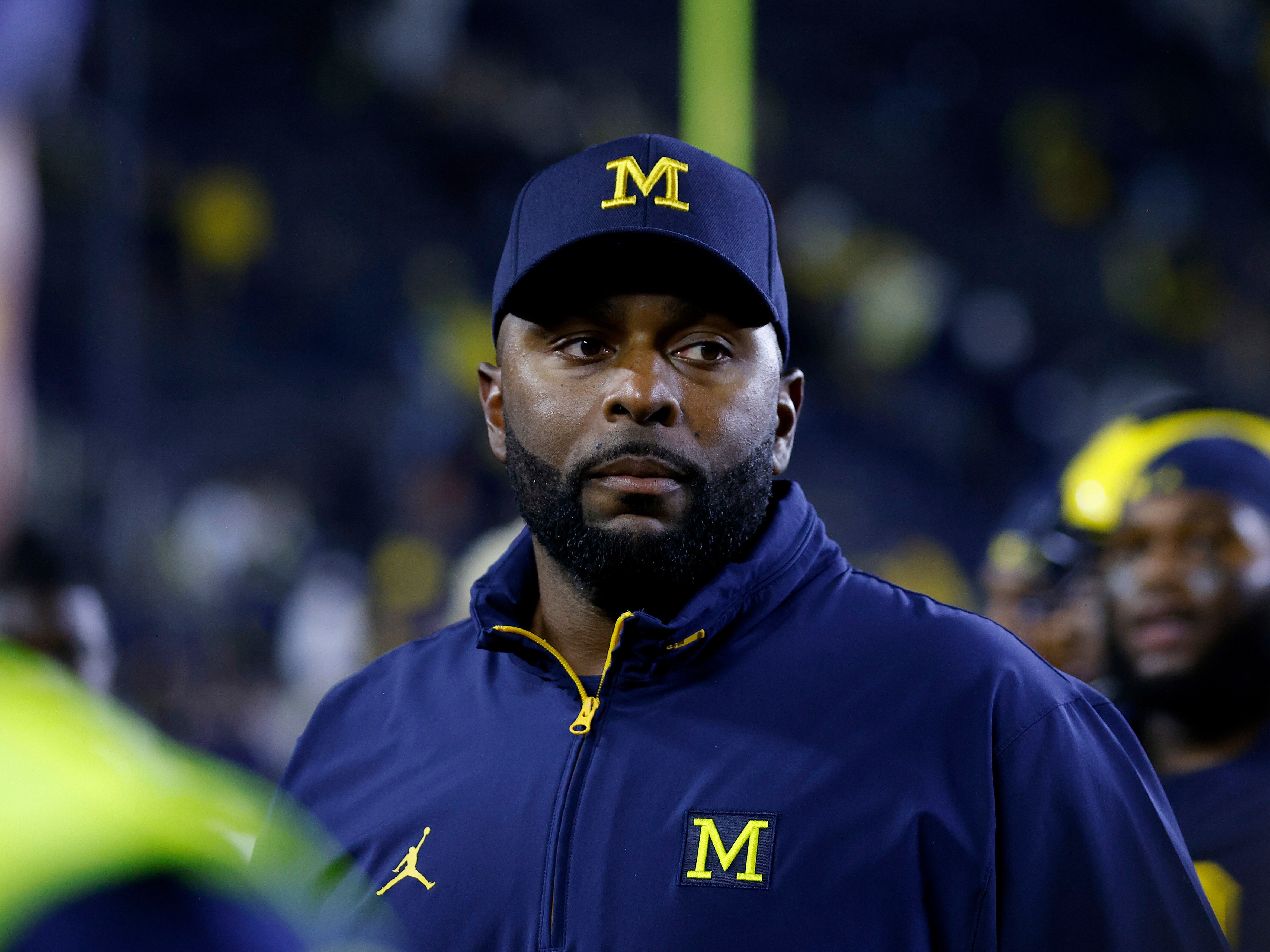 caption: Then-Michigan football coach Sherrone Moore walks off the field following a game Aug. 30, 2025, in Ann Arbor, Mich. Moore has been charged with three crimes, including felony home invasion and stalking, after prosecutors said he "barged his way" into the apartment of a woman with whom he had been having an affair.