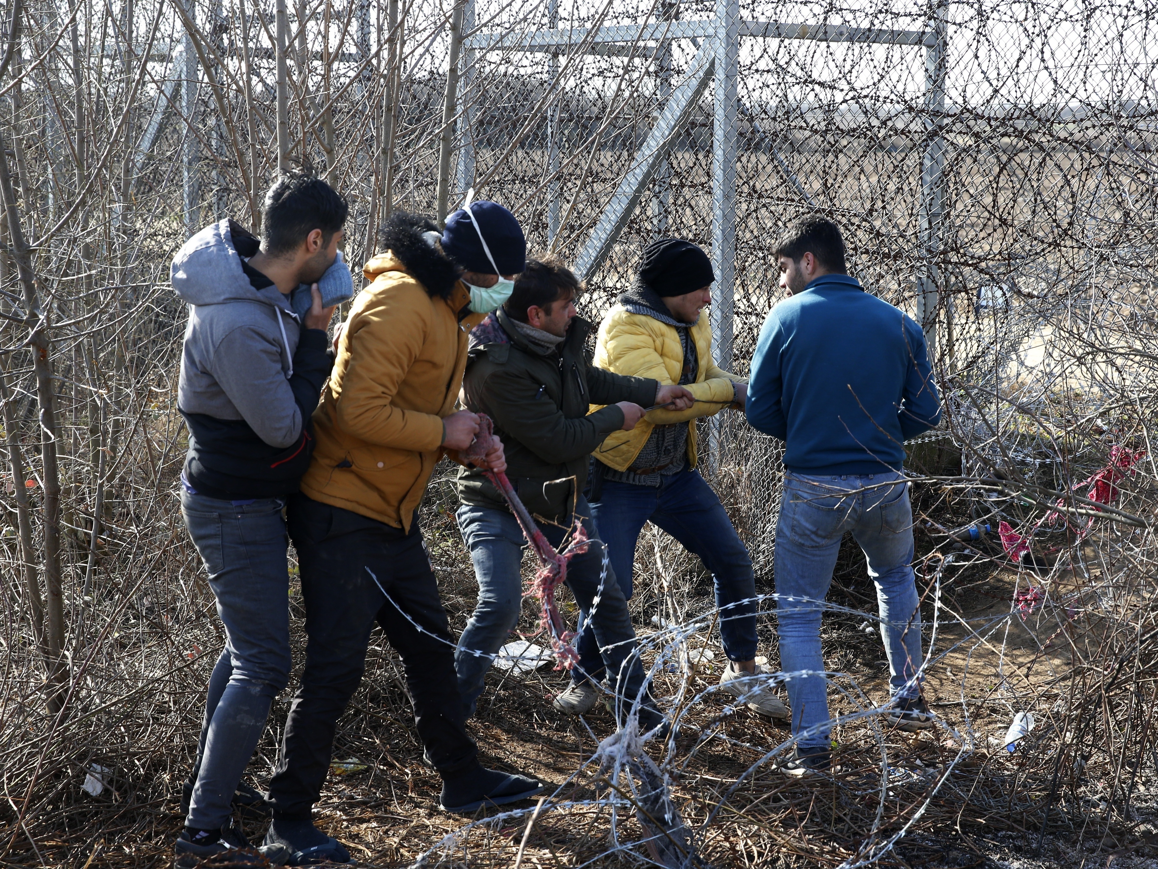 caption: Migrants try to cut the fence at the Turkish-Greek border near the Pazarkule border gate in Edirne, Turkey, on Monday. Thousands of migrants and refugees massed at Turkey's western frontier, trying to enter Greece by land and sea after Turkey said its borders were open to those hoping to head to Europe.