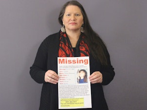 caption: Carolyn DeFord poses with the missing persons poster for her mother, Leona Kinsey, who went missing in October 1999.