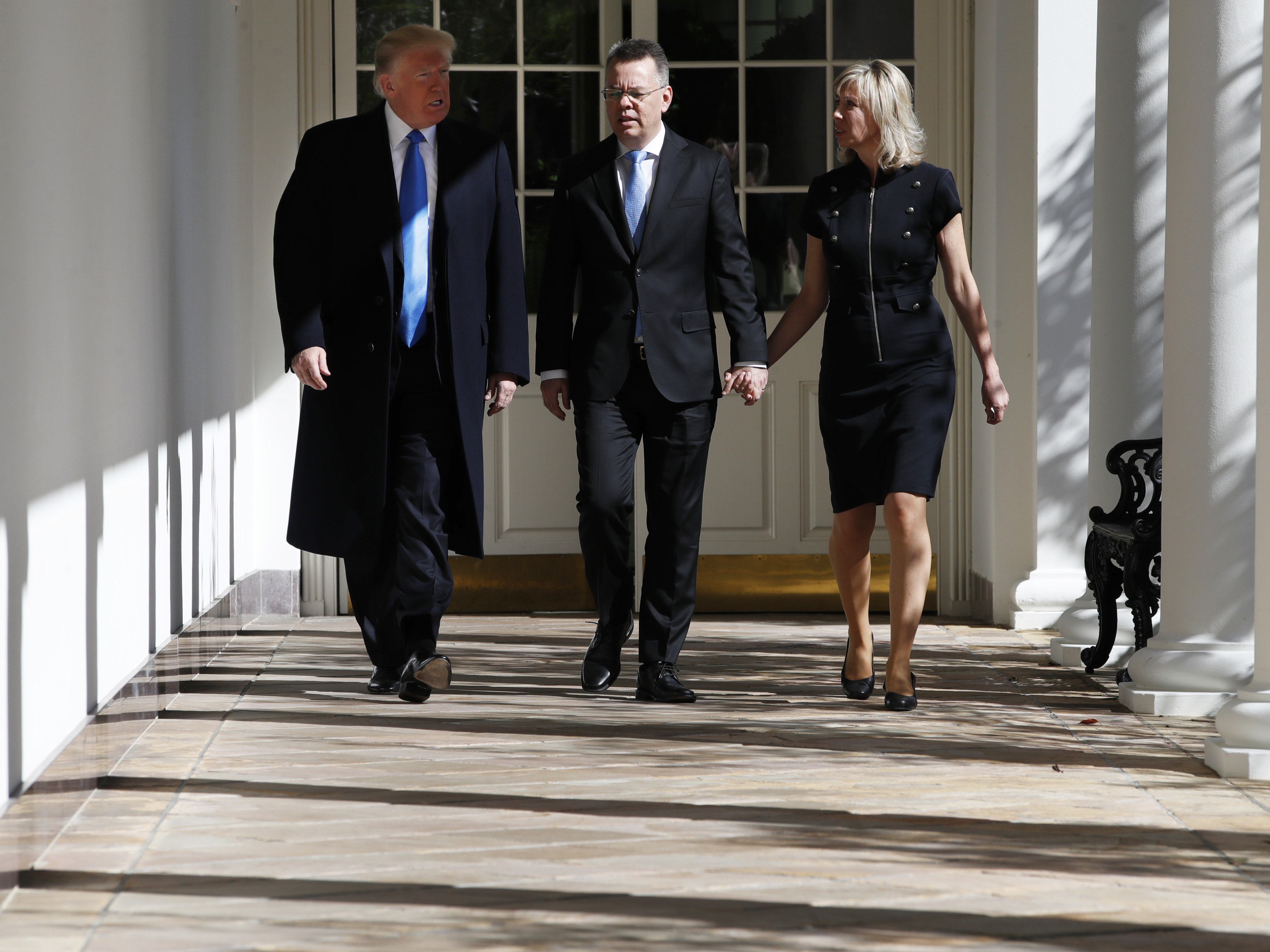 caption: Andrew Brunson walks down the colonnade of the White House on Saturday, flanked by his wife, Norine, and President Trump.
