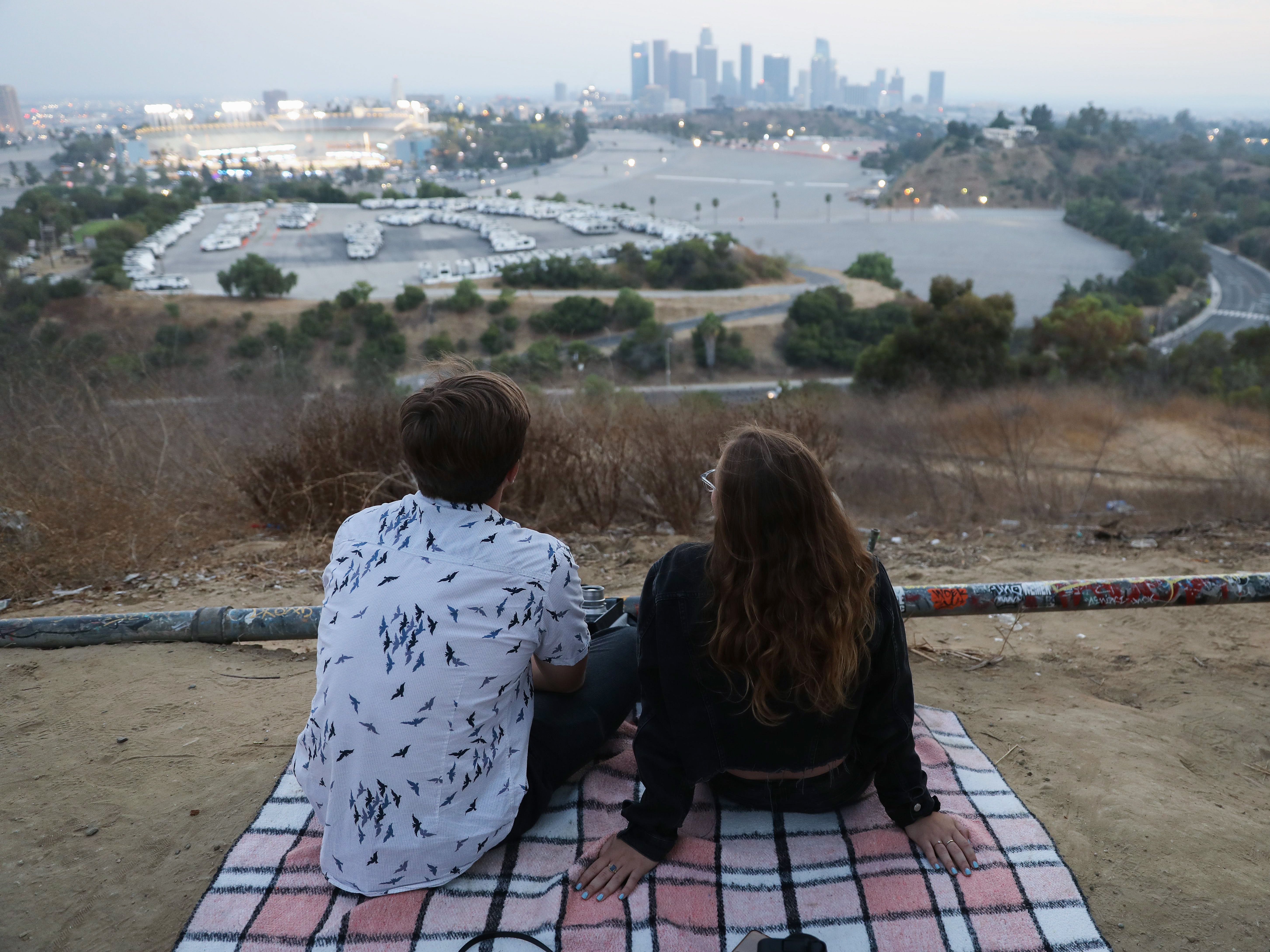 caption: People gather for a picnic on a hillside overlooking Dodger Stadium in Los Angeles during a game Saturday. Spectators are currently not allowed to attend Major League Baseball games in order to prevent the spread of the coronavirus.