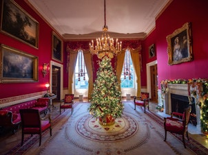 caption: A Christmas tree stands in the Red Room during a press preview of White House holiday decorations on Nov. 29.
