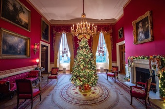 caption: A Christmas tree stands in the Red Room during a press preview of White House holiday decorations on Nov. 29.