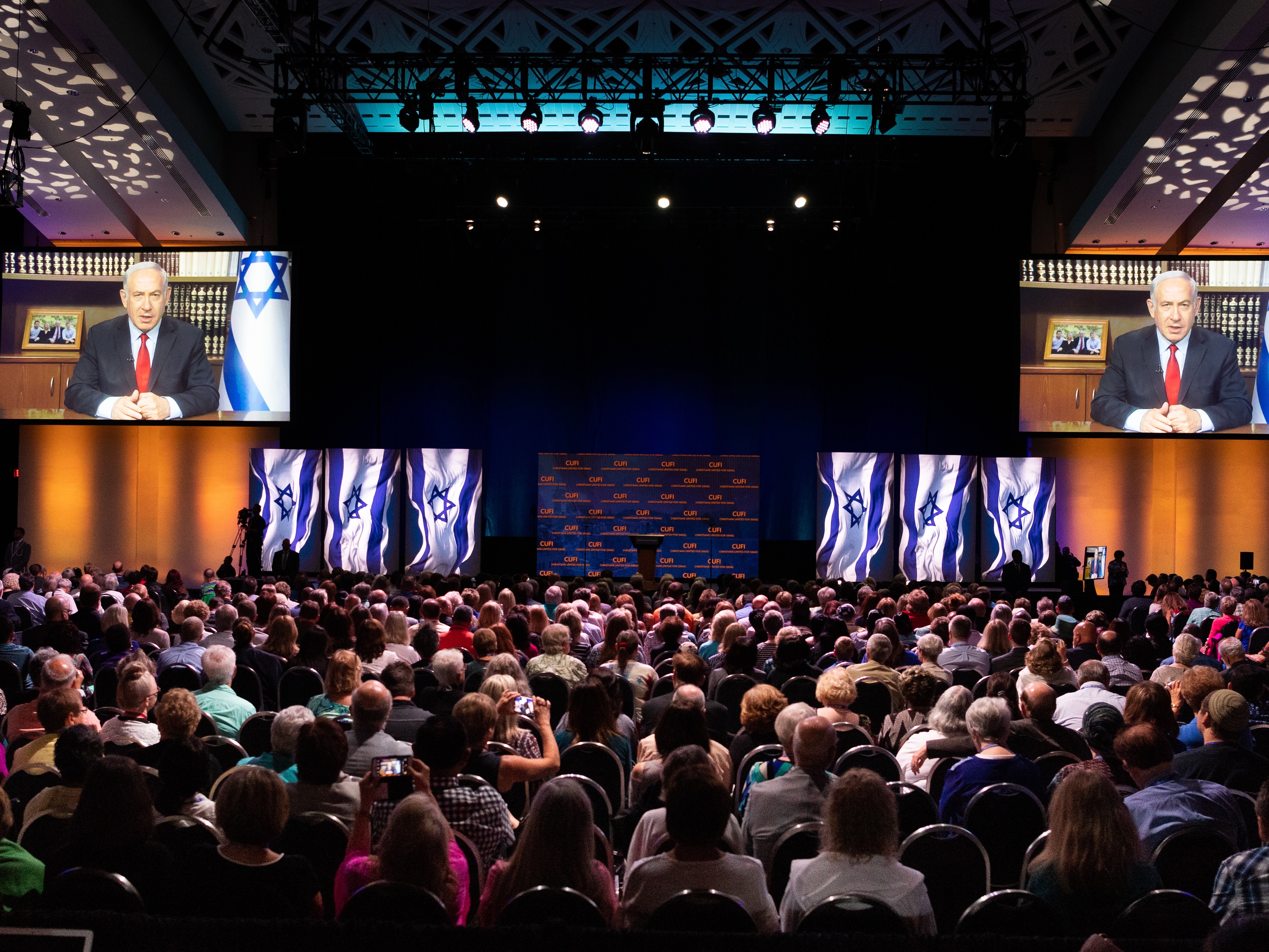 caption: Benjamin Netanyahu, Prime Minister of Israel, speaking via live video conference at the Christians United for Israel's summit in 2018. Recent polling shows a sharp drop in support for Israel among young conservatives.