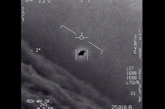 caption: In this image from 2015 video provided by the Department of Defense, an unexplained object is seen as it is tracked soaring high along the clouds, traveling against the wind.