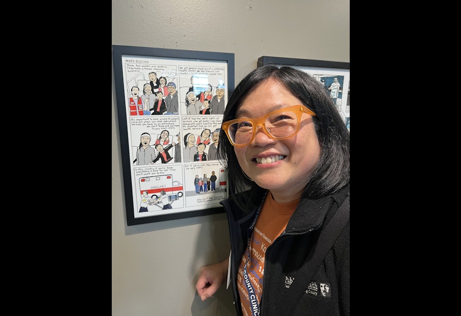 caption: Meredith Li-Vollmer stands in front of one of the comics she created for the King County health department.