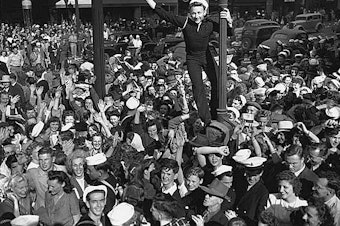 caption: Sailor climbing a lamppost on V-J Day in Seattle, August 14, 1945.