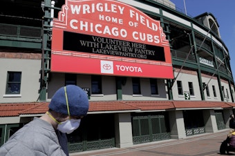 caption: Wrigley Field's marquee displays Lakeview Pantry volunteer information in Chicago on Thursday, after MLB announced the 2020 season will be delayed because of the coronavirus.