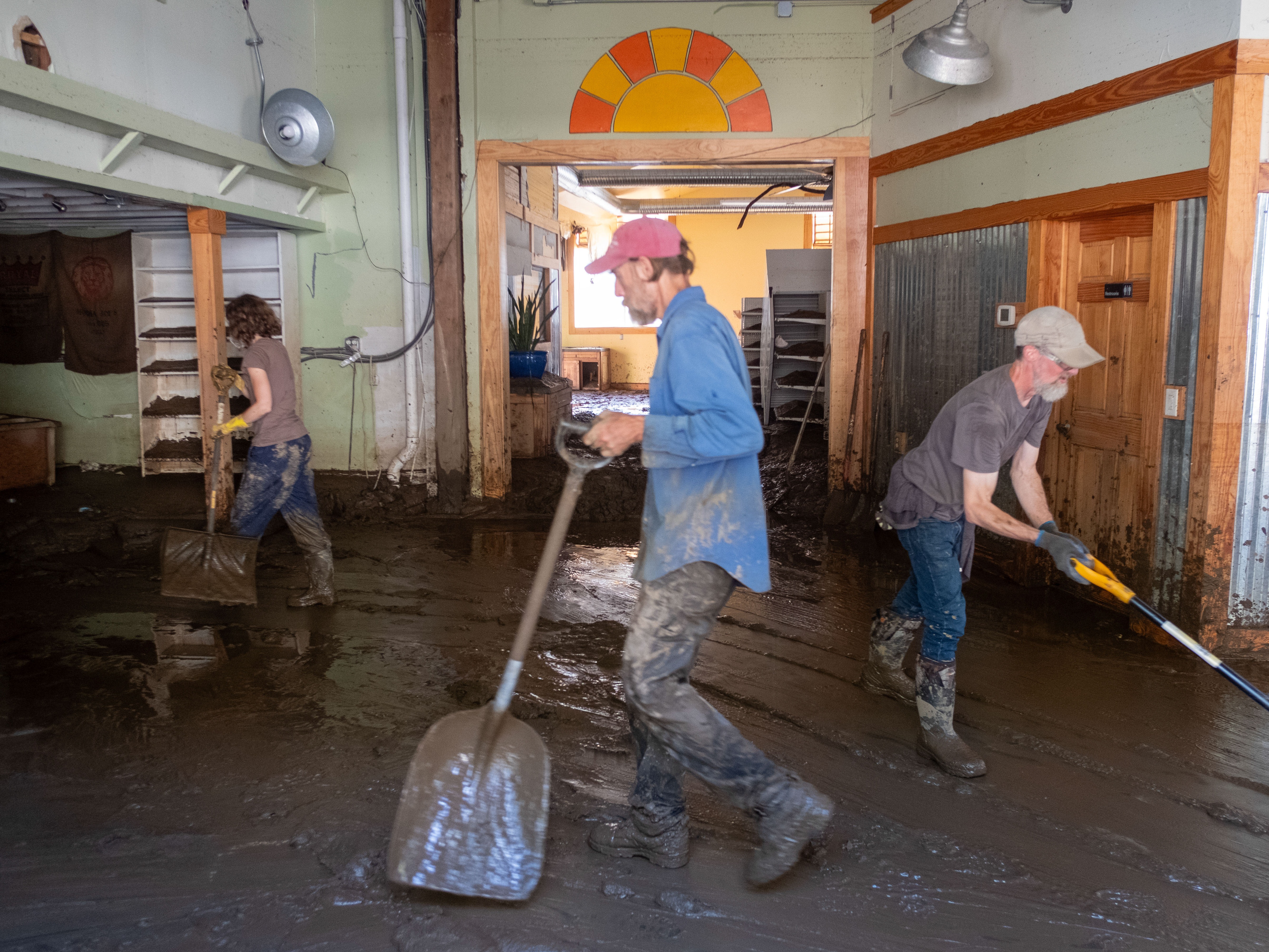 caption: Residents work hard to shovel the mud out of Marshall, N.C.'s natural grocery store. French Broad River, which runs through town, crested over 24 feet during Tropical Storm Helene. The river level has gone down, but left behind knee-deep sediment inside the buildings.