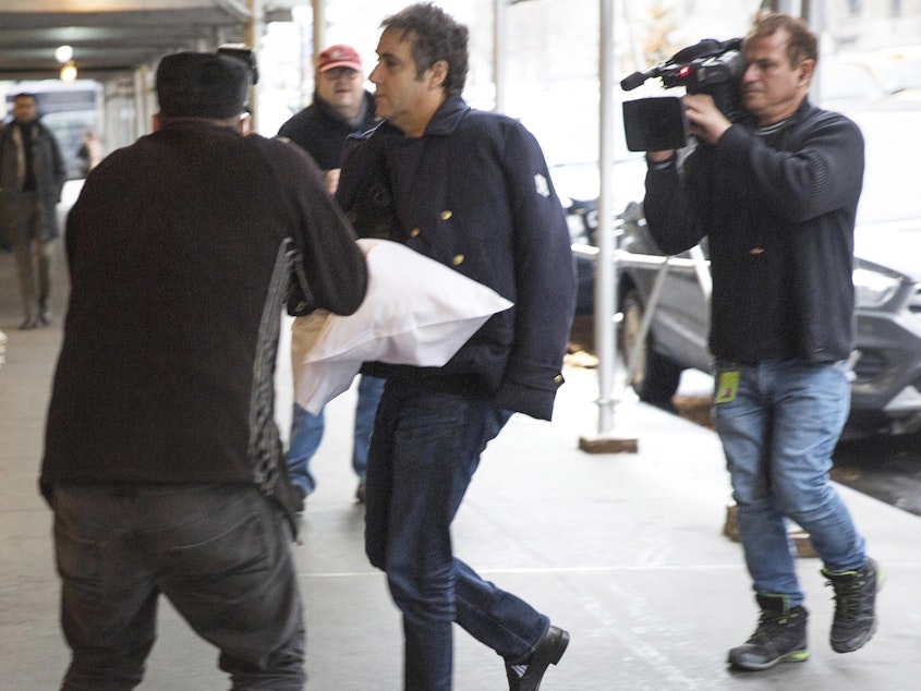 caption: Michael Cohen dodges photojournalists as he returns home in New York City. The former fixer for Donald Trump says he's postponing testimony planned for a House hearing next month.