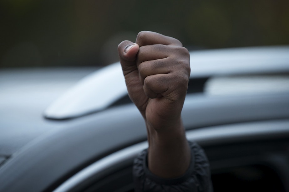 caption: A driver raises their fist in the air while passing a large gathering of hundreds celebrating after Joe Biden was officially named the president elect on Saturday, November 7, 2020, at the intersection of 10th Avenue and East Pine Street in Seattle.