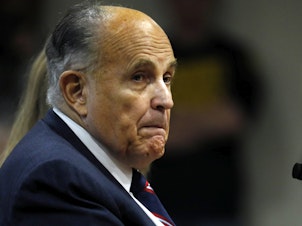 caption: Rudy Giuliani, personal lawyer of President Trump, looks on during an appearance before Michigan's House Oversight Committee in Lansing, Mich., on Dec. 2.