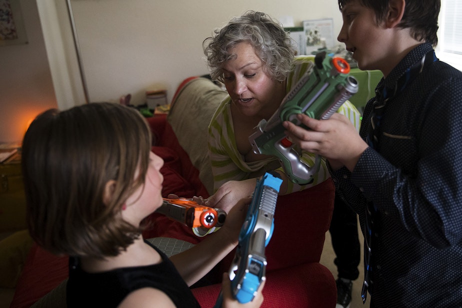 caption: Elthea Farr, center, helps her kids, Amaleia, 8, and Xaven, 11, figure out how to use Xaven's new laser tag guns, a birthday present from his aunt, on Sunday, April 7, 2019, at their home in Seattle. 