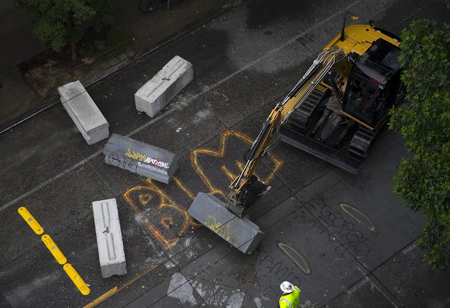caption: Seattle Department of Transportation employees remove barricades after the Capitol Hill Organized Protest zone was cleared by Seattle Police Department officers early Wednesday morning, July 1, 2020, at the intersection of 12th Avenue and East Pine Street in Seattle. 