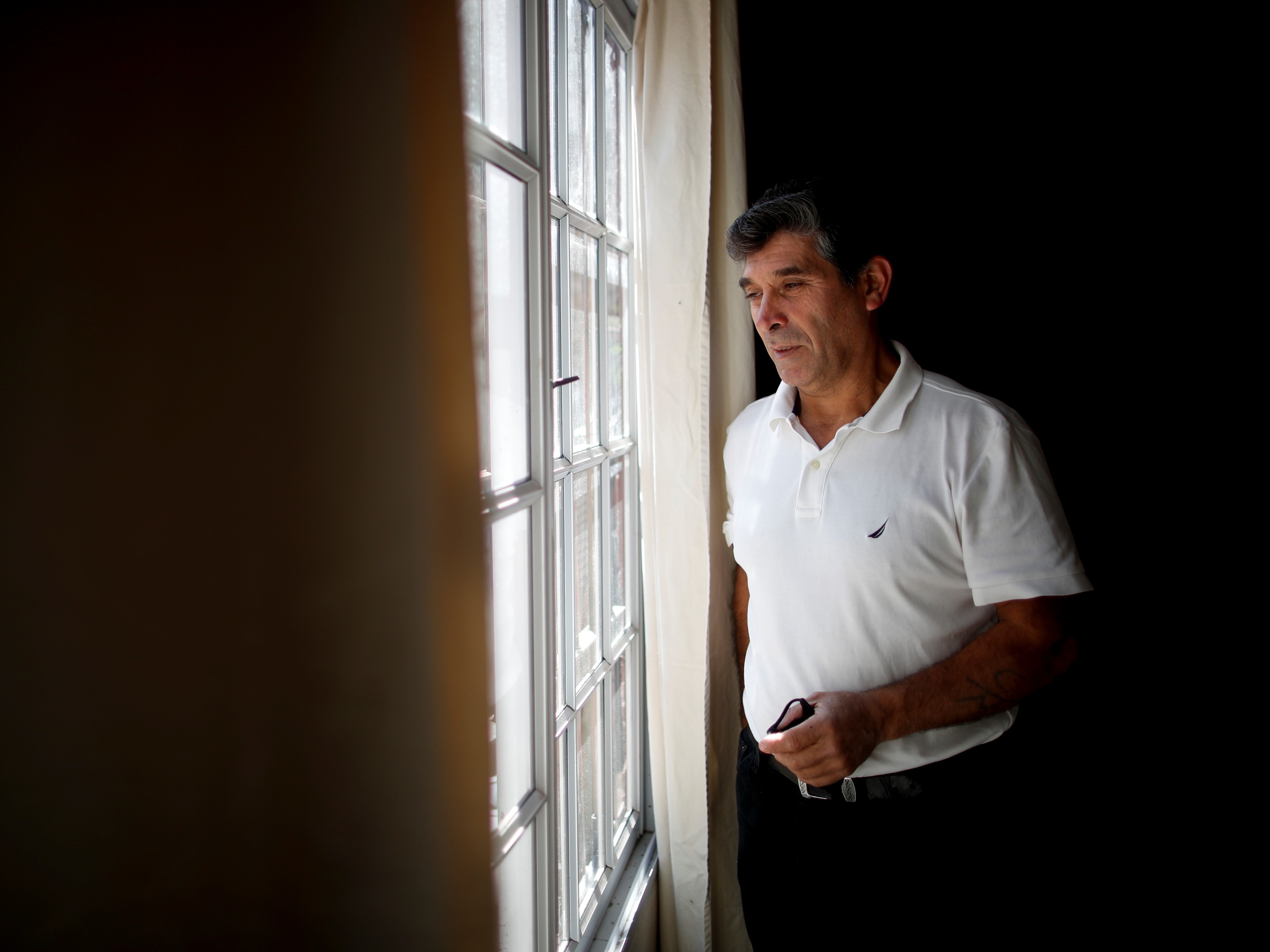 caption: Claudio Rojas, a 55-year-old handyman who was deported from the U.S. in 2019, poses for a photo in his home in Moreno, Argentina, Saturday, May 8. His wife, two sons and two grandsons remained in Florida.