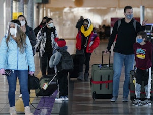 caption: Masked travelers head through the main terminal of Denver International Airport on Dec. 31. Starting Feb. 1, travelers will be required to wear face masks on nearly all forms of public transportation.