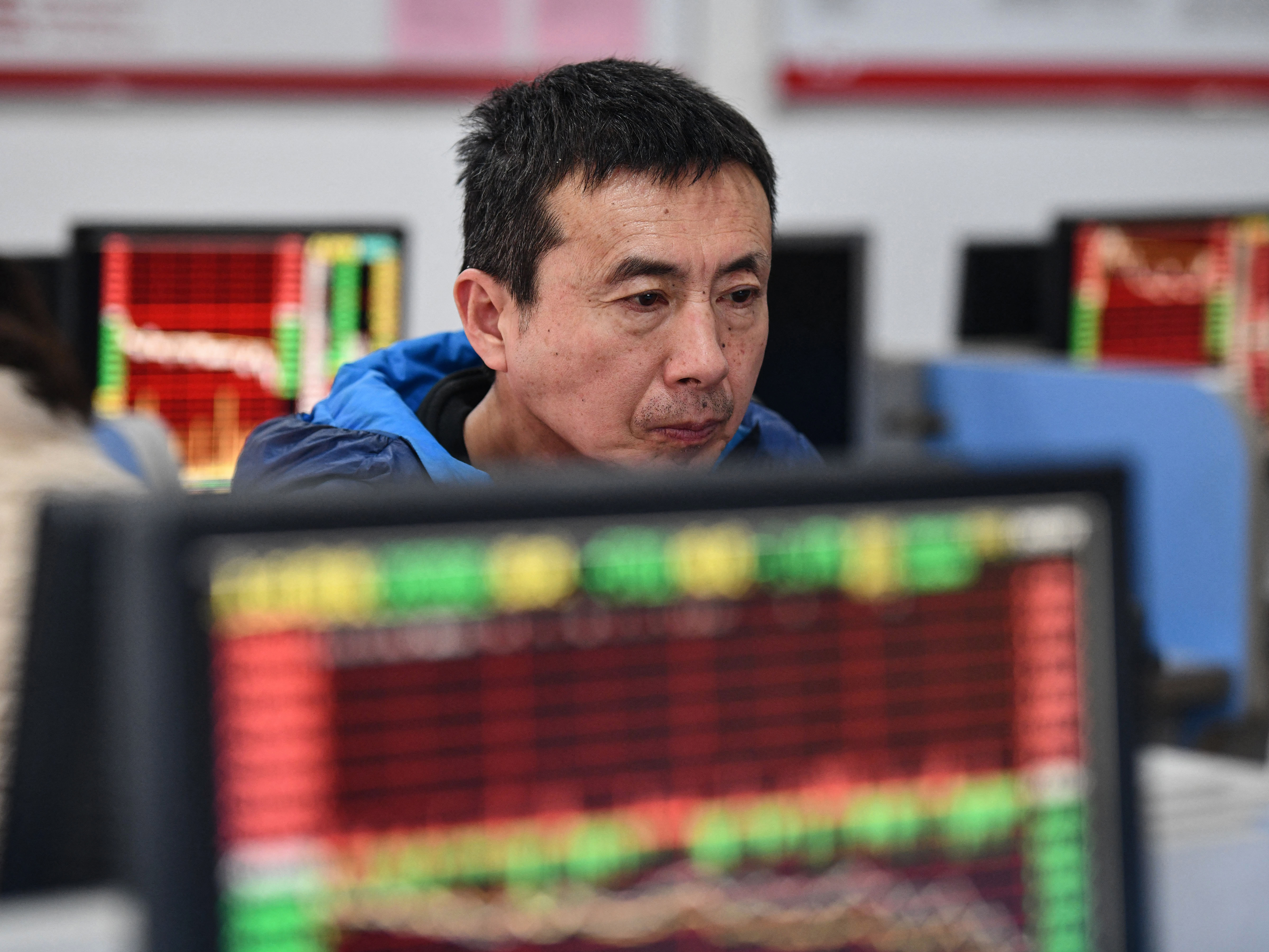 caption: An investor looks at screens showing stock market movements at a securities company in Fuyang in China's eastern Anhui province on Jan. 17.