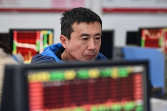 caption: An investor looks at screens showing stock market movements at a securities company in Fuyang in China's eastern Anhui province on Jan. 17.