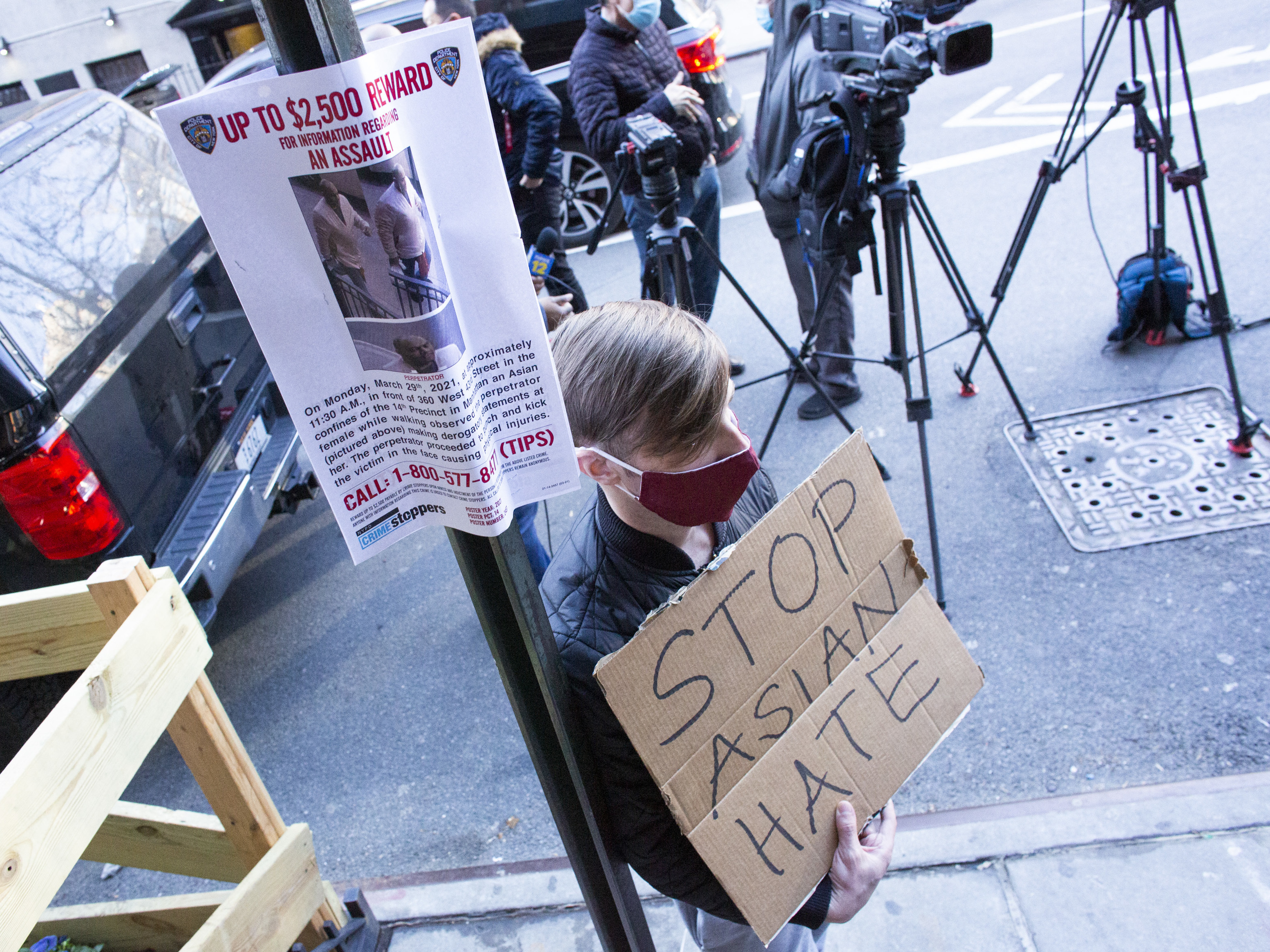 caption: A man holds a sign at an Asian American anti-violence press conference on Tuesday, outside the building where a 65-year-old Asian woman was physically and verbally attacked in New York City. Police said Wednesday that Brandon Elliot, 38, had been arrested and charged with crimes which include assault as a hate crime.