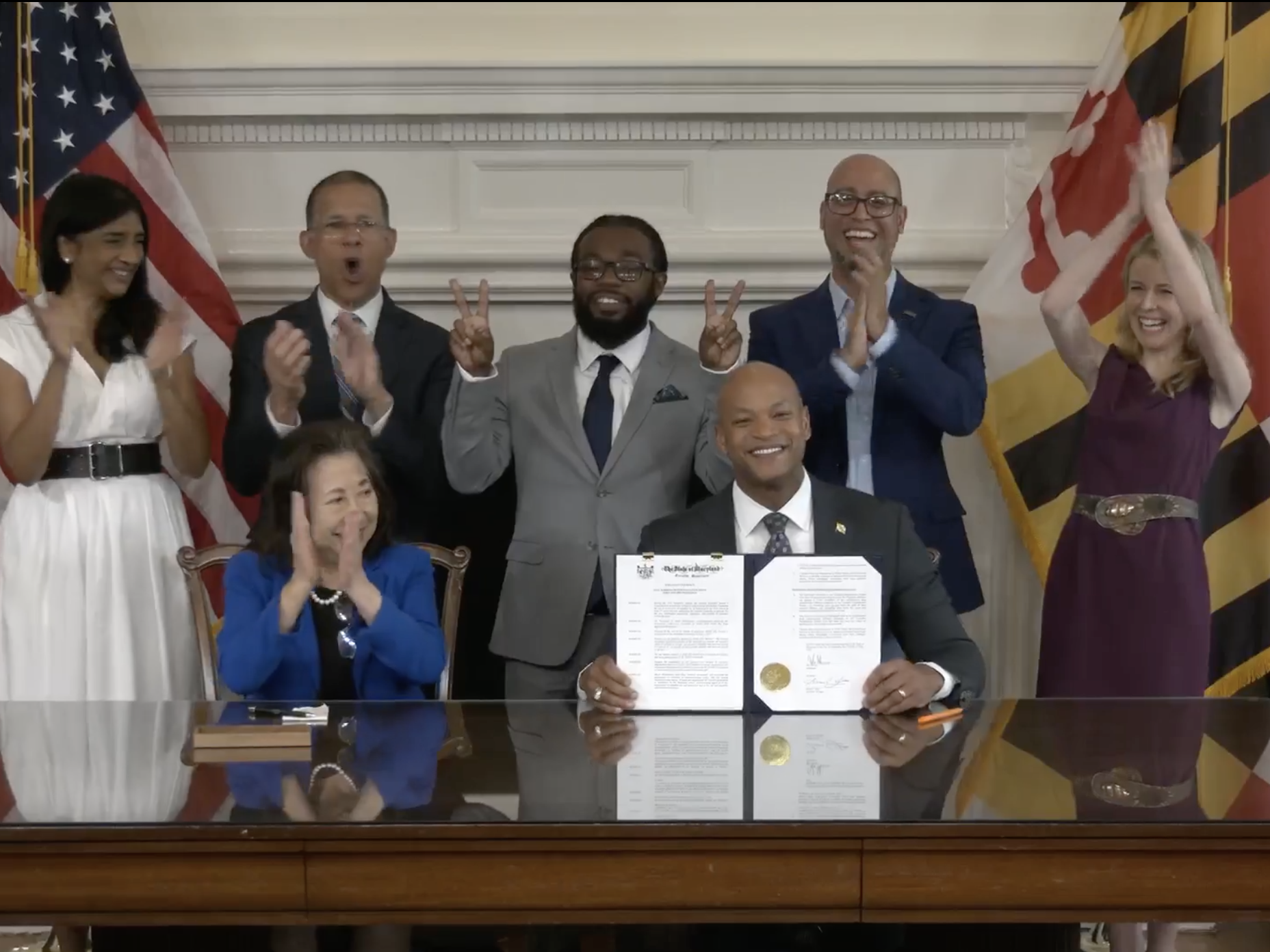 caption:  Gov. Wes Moore, center, holds an executive order authorizing pardons for at least 175,000 criminal convictions related to marijuana. Legalization, Moore said, “doesn't erase the fact that Black Marylanders were three times more likely to be arrested for cannabis than white Marylanders before legalization."